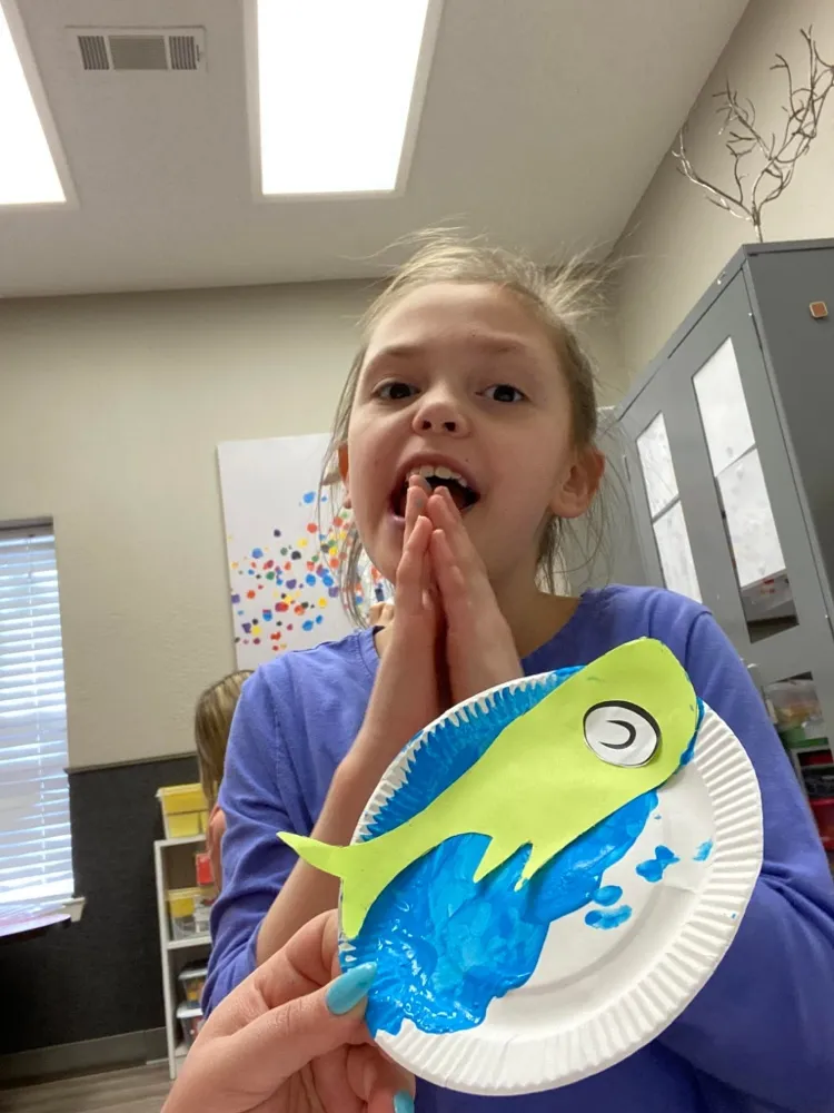 Child smiling after finishing a fish art project